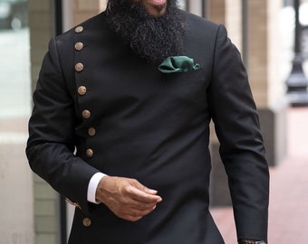 May include: A man wearing a black long-sleeved jacket with gold buttons and a green pocket square. He is wearing black pants and a watch on his left wrist.