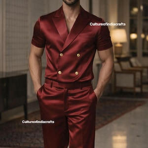 Könnte beinhalten: Ein burgunderfarbener Satinanzug mit einer doppelreihigen Jacke mit kurzen Ärmeln und passender Hose. Die Jacke hat goldfarbene Knöpfe. Das Outfit wird mit schwarzen Anzugschuhen getragen. Der Text "Cultureofindiacrafts" ist sichtbar.