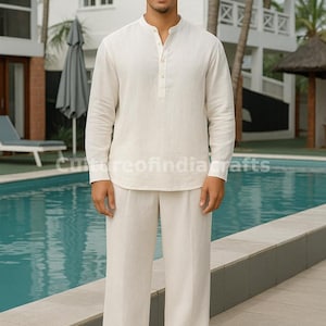 Puede incluir: Un conjunto de lino color crema, que consta de una camisa Henley de manga larga y pantalones anchos a juego. El conjunto se usa con sandalias beige. El fondo incluye una piscina y follaje tropical. El texto "Cureofindia crafts" es visible.