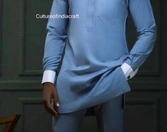 Puede incluir: Un hombre con una camisa de manga larga azul y negra con cuello blanco y pantalones a juego. Lleva gafas de sol y tiene barba.