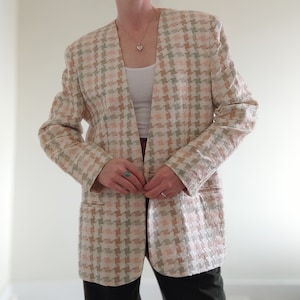 Könnte beinhalten: Ein langärmliger Blazer mit einem Hahnentrittmuster in Rosa-, Grün- und Weißtönen. Der Blazer hat einen einzigen Knopfverschluss und einen V-Ausschnitt.