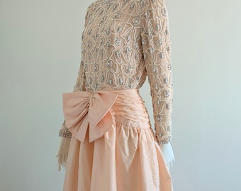 Puede incluir: Un vestido de gala de color melocotón con un corpiño de cuentas y un gran lazo en la cintura.