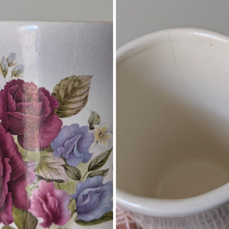 May include: A white ceramic mug with a floral design featuring pink and purple roses, blue flowers, and green leaves. The mug has a crack on the side.