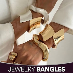 May include: Gold and silver-toned jewelry bangles. The image shows multiple wide, curved bangles in gold and silver. The bangles have a smooth, polished finish. The word "JEWELRY BANGLES" is displayed at the bottom of the image.