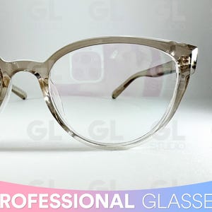 May include: Clear-framed eyeglasses with a cat-eye shape. The glasses have a light brown tint and thin temples. The text "PROFESSIONAL GLASSES" is at the bottom of the image.