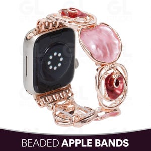 Peut inclure: Un bracelet de montre connectée en or rose composé de maillons alternant des roses en métal ajouré et des éléments lisses en forme de pétales rose clair irisé. Le bracelet est fixé à un boîtier de montre argenté avec un dos noir et un capteur.