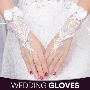 May include: White lace wedding gloves with a bow at the wrist and finger loops. The gloves are adorned with delicate floral embroidery and sparkling embellishments. The text "WEDDING GLOVES" is at the bottom of the image.