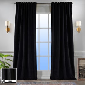 Pode incluir: Duas cortinas blackout pretas penduradas em uma janela. As cortinas estão totalmente fechadas e bloqueiam toda a luz. As cortinas são feitas de um tecido macio e luxuoso.