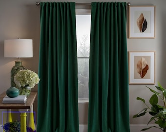 May include: A pair of dark green blackout curtains hanging in a window. The curtains are made of a thick, textured fabric and are fully drawn, blocking out all light. The curtains are hung on a silver curtain rod.