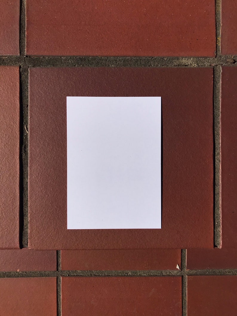 May include: A blank white card on a red brick background.