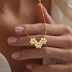 May include: Gold necklace with a paw print design featuring the names Victoria, Sasha, and Sophie.