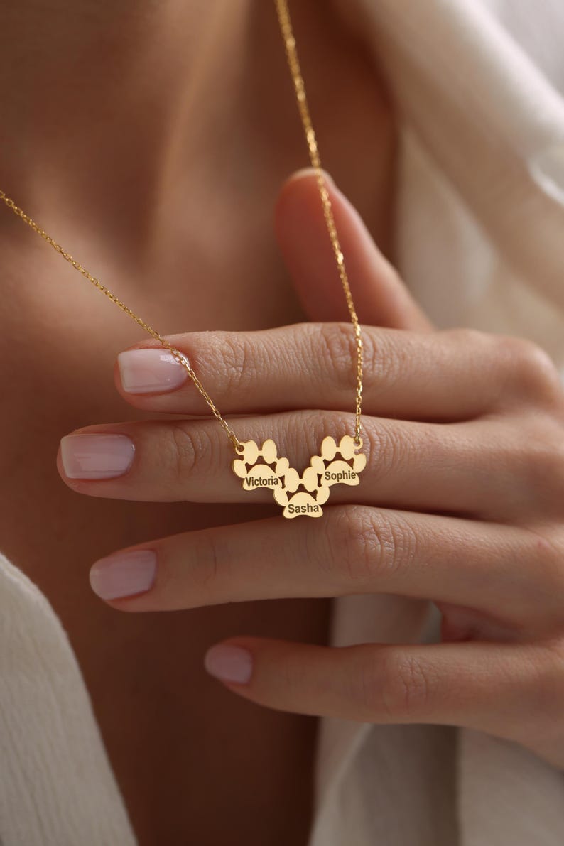 May include: Gold necklace with a paw print design featuring the names Victoria, Sasha, and Sophie.