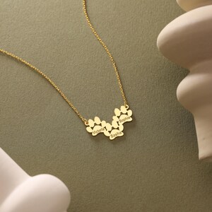 May include: Gold necklace with a paw print design featuring the names Victoria, Sasha, and Sophie.