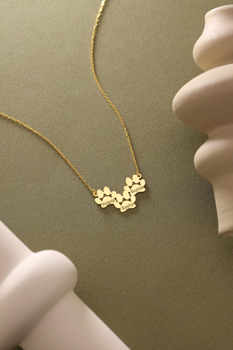 May include: Gold necklace with a paw print design featuring the names Victoria, Sasha, and Sophie.
