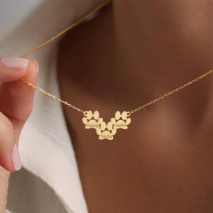 May include: Gold necklace with three paw print charms, each engraved with a name: Victoria, Sasha, and Sophie.