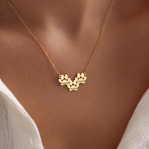 May include: Gold necklace with a paw print design featuring the names Victoria, Sophie, and Sasha.