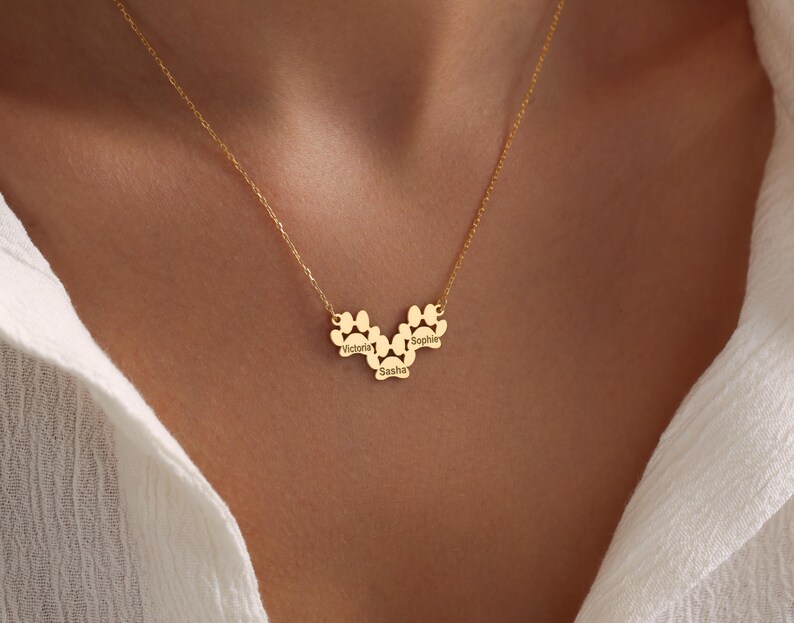 May include: Gold necklace with a paw print design featuring the names Victoria, Sophie, and Sasha.