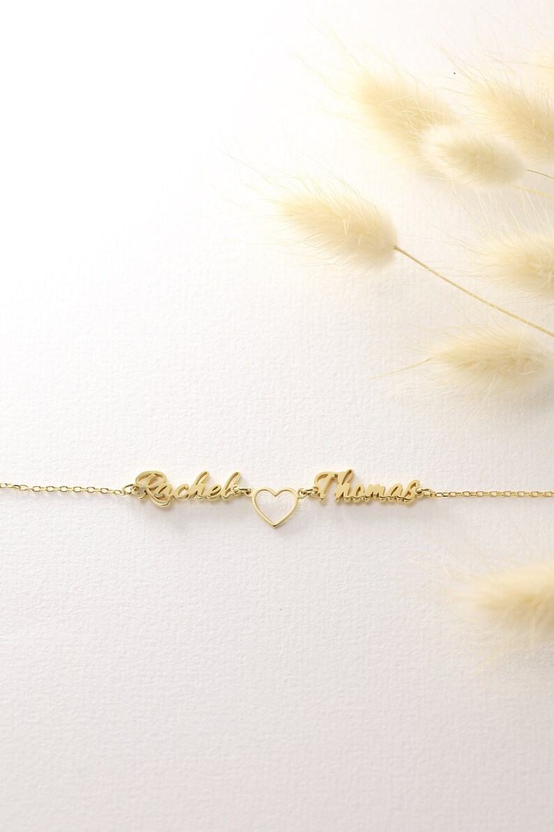 Pu&ograve; includere: Collana in oro con i nomi "Rachel" e "Thomas" separati da un ciondolo a forma di cuore.
