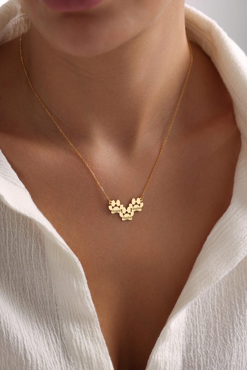 May include: Gold necklace with three paw print charms, each engraved with a name: Victoria, Sasha, and Sophie.