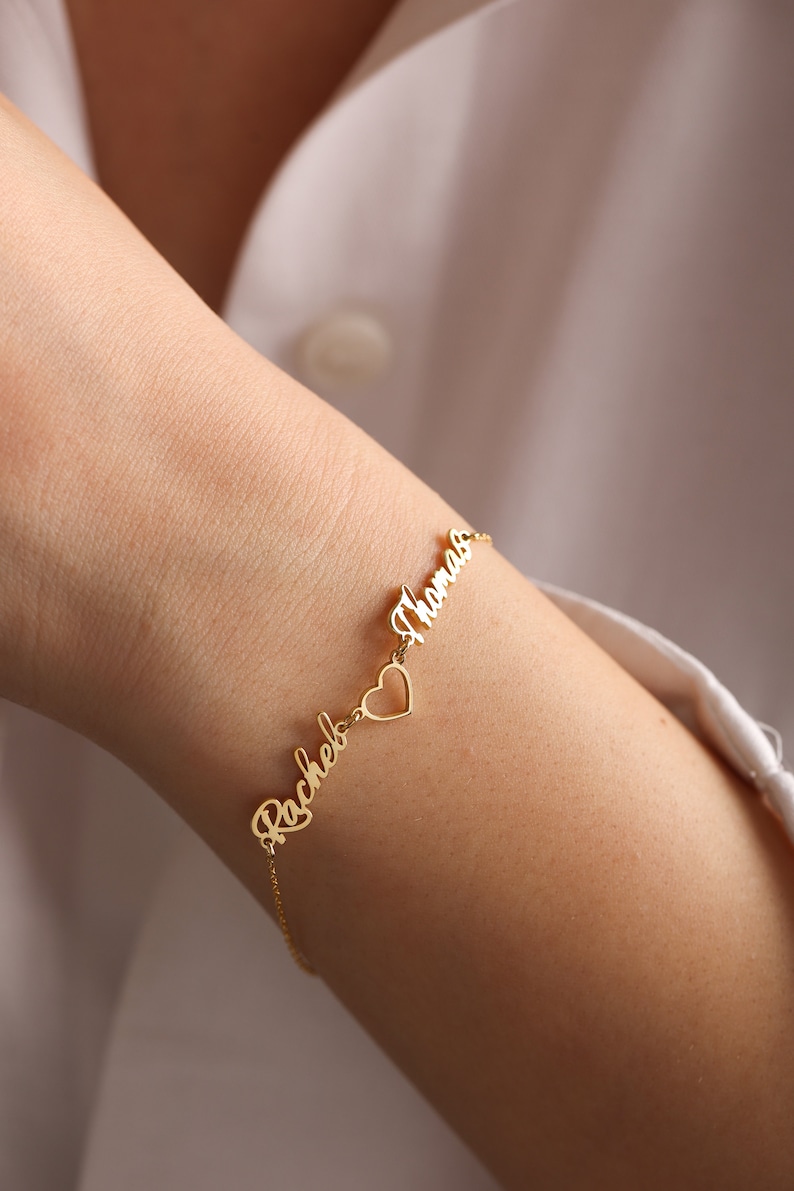 Pu&ograve; includere: Braccialetto in oro con i nomi "Rachel" e "Thomas" collegati da un ciondolo a forma di cuore.