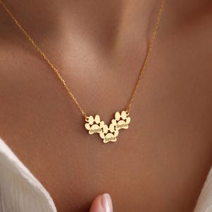May include: Gold necklace with three paw print charms, each engraved with a name: Victoria, Sasha, and Sophie.