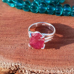 K&ouml;nnte beinhalten: Ein silberner Ring mit einem gro&szlig;en, rohen, rosafarbenen Rubin-Edelstein. Der Ring ist mit "925" und "APS Silvershop" gekennzeichnet.