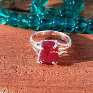 K&ouml;nnte beinhalten: Ein Silberring mit einem roten Rubin-Edelstein. Der Ring ist mit der Nummer "925" und dem Text "APSilverShop" gekennzeichnet.