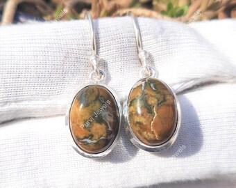 May include: A pair of silver dangle earrings with oval-shaped brown, green, and white jasper stones. The earrings have a simple design and are perfect for everyday wear.