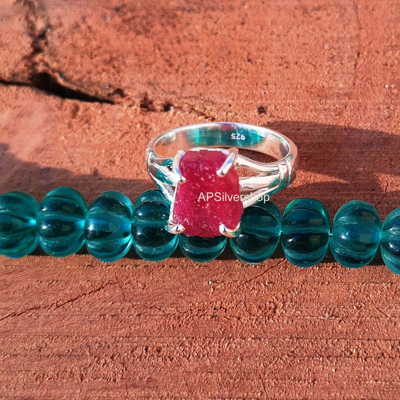 K&ouml;nnte beinhalten: Ein silberner Ring mit einem gro&szlig;en, roten, facettierten Rubin-Edelstein. Der Ring ist mit der Gr&ouml;&szlig;e "SZ6" gekennzeichnet.