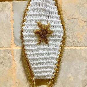 May include: White crocheted mask with a gold star and gold trim.