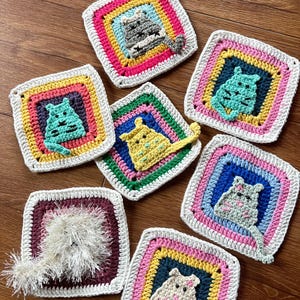 May include: Eight crocheted squares with colorful borders and a cat appliqu&eacute; in the center of each square. The cats are different colors and have different expressions.