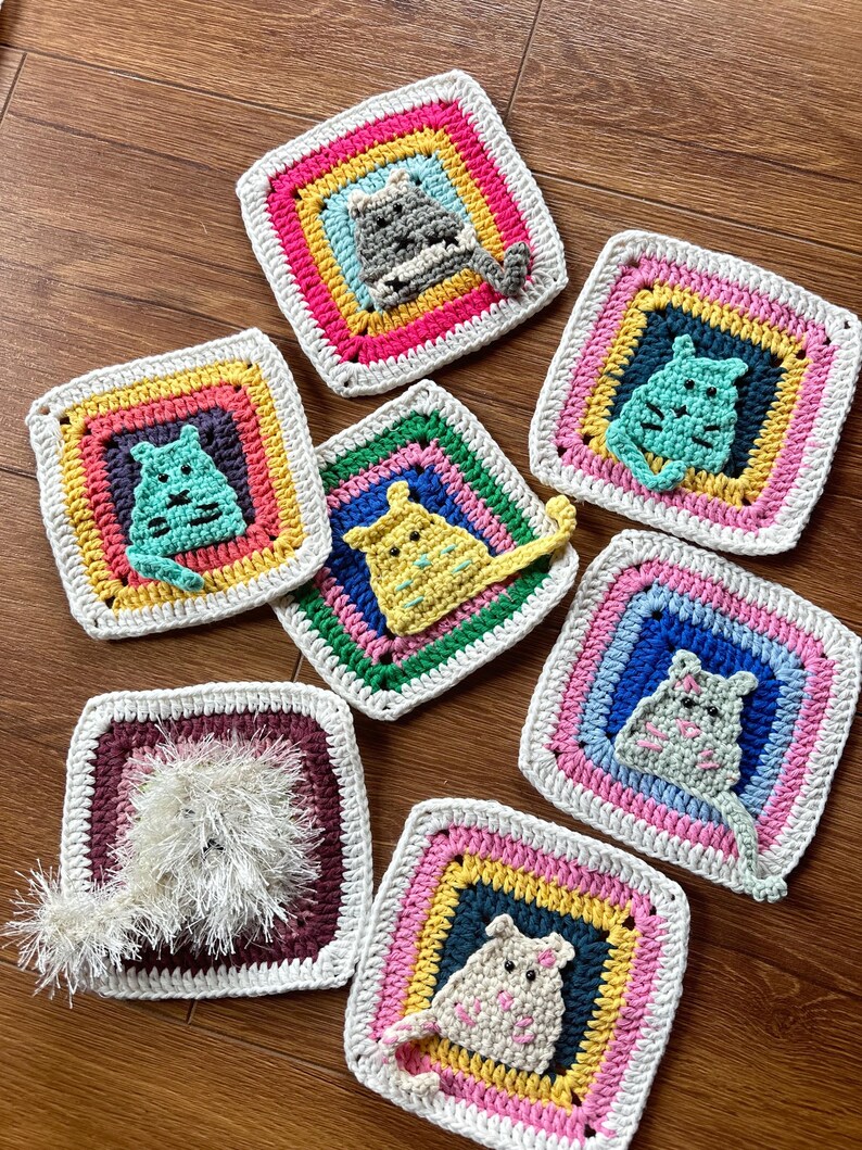 May include: Eight crocheted squares with colorful borders and a cat appliqu&eacute; in the center of each square. The cats are different colors and have different expressions.