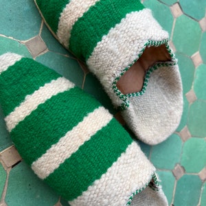 May include: A pair of green and white striped slippers. The slippers are made of a soft, woven fabric and have a pointed toe.