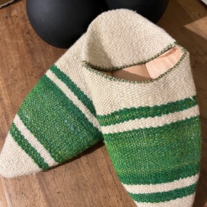 May include: A pair of white and green striped slippers. The slippers are made of woven fabric and have a pointed toe.