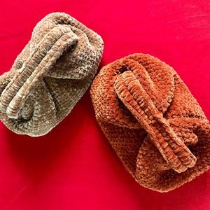May include: Two crocheted bags, one brown and one orange, with a fuzzy texture. The bags are made with a knotted stitch and have a unique, hand-crafted look.