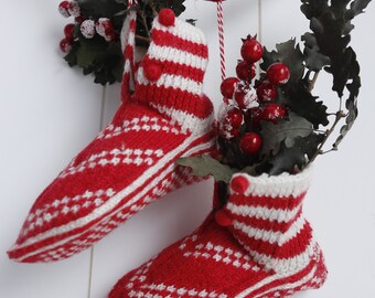 May include: Two red and white striped knitted stockings with pom-poms hanging from a rope with red and white twine. The stockings are decorated with holly and red berries.