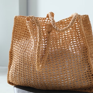May include: A large, brown, crocheted tote bag with a mesh design. The bag has two long straps.