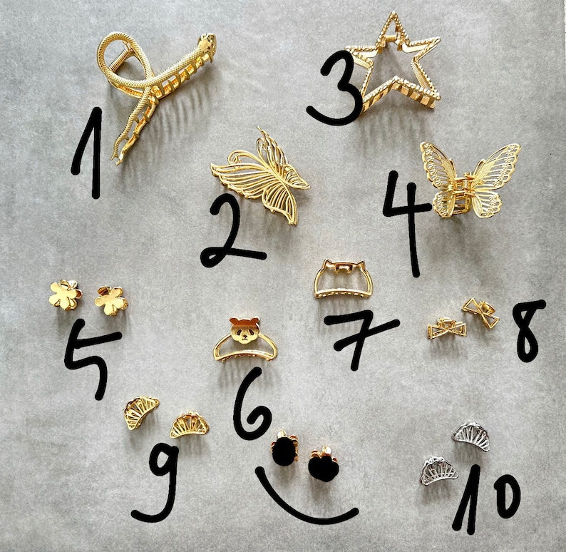 Pu&ograve; includere: Un set di dieci fermagli per capelli e accessori dorati, tra cui un fermaglio a forma di stella, fermagli a farfalla e piccoli fermagli a forma di fiore. I fermagli sono numerati da 1 a 10.