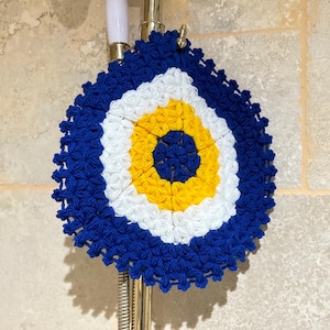 May include: A blue, white, and yellow crocheted evil eye wall hanging. The evil eye is a symbol of protection against negative energy.
