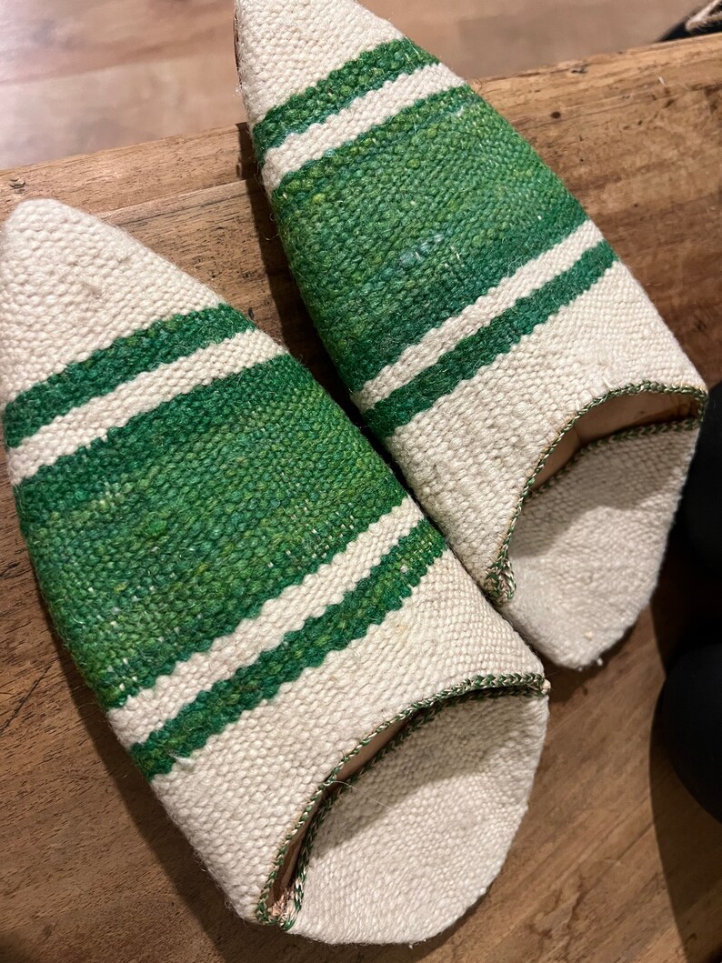 May include: A pair of white and green striped slippers. The slippers are made of a woven fabric and have a pointed toe.