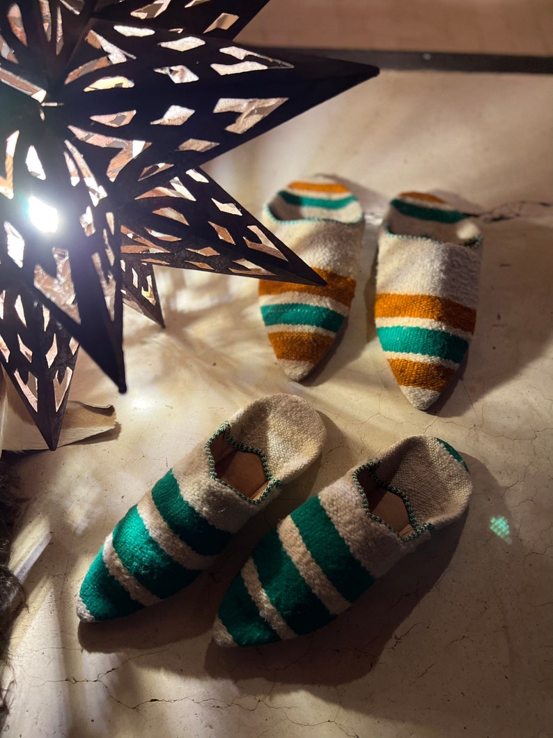 May include: A pair of green and white striped slippers with a pointed toe. The slippers are made of a soft, woven fabric and have a comfortable fit.