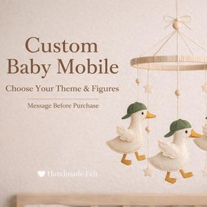 May include: A custom baby mobile featuring three white felt ducks wearing green caps, with yellow beaks and feet. The mobile includes star and bead accents, suspended from a circular frame. Text on the image reads "Custom Baby Mobile" and "Handmade Felt".