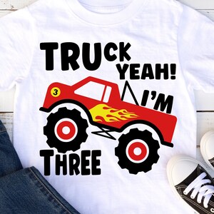 Pode incluir: Camiseta branca com um gráfico de caminhão monstro vermelho e o texto "Truck Yeah! I'm Three".