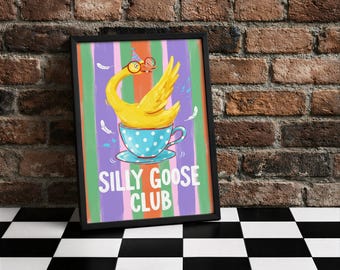 Könnte beinhalten: Gerahmter Kunstdruck mit einer Illustration einer gelben Gans mit Brille, die in einer blau gepunkteten Tasse sitzt. Der Text "SILLY GOOSE CLUB" befindet sich darunter, vor einem farbenfrohen gestreiften Hintergrund.