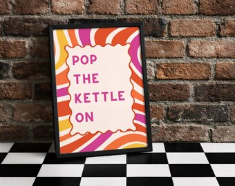 Könnte beinhalten: Gerahmter Kunstdruck mit dem Text "POP THE KETTLE ON" in Rosa. Das Kunstwerk hat ein Retro-Design mit orangefarbenen, gelben und rosa Wellenlinien. Der schwarze Rahmen wird vor einer Backsteinmauer präsentiert.