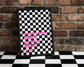 Könnte beinhalten: Ein gerahmter Druck mit einem schwarz-weißen Schachbrettmuster. Der Druck zeigt den Text "IF YOU DON'T HAVE ANYTHING NICE TO SAY, COME SIT BY ME" in rosa Buchstaben. Der Rahmen ist schwarz und der Hintergrund ist eine Backsteinmauer.