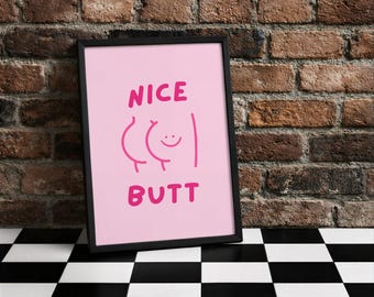 Könnte beinhalten: Gerahmter rosa Kunstdruck mit den Worten "NICE BUTT" in Pink, zusammen mit einer Cartoon-Illustration eines lächelnden Hinterns. Das Kunstwerk wird vor einer Backsteinmauer und einem schwarz-weiß karierten Boden präsentiert.