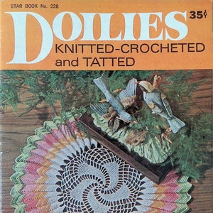 May include: A vintage crochet doily pattern book cover featuring a colorful crocheted doily on a wooden surface. The cover also features a pair of blue birds on a branch and the text "Doilies Knitted-Crocheted and Tatted" and "Star Book No. 228 35¢".