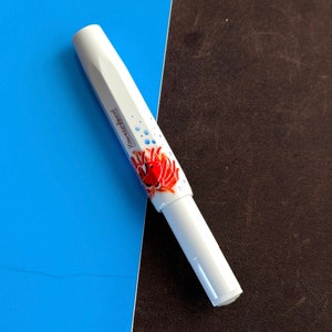 May include: White pen with a red and orange fish design and the word "KAWECO" printed on the side.
