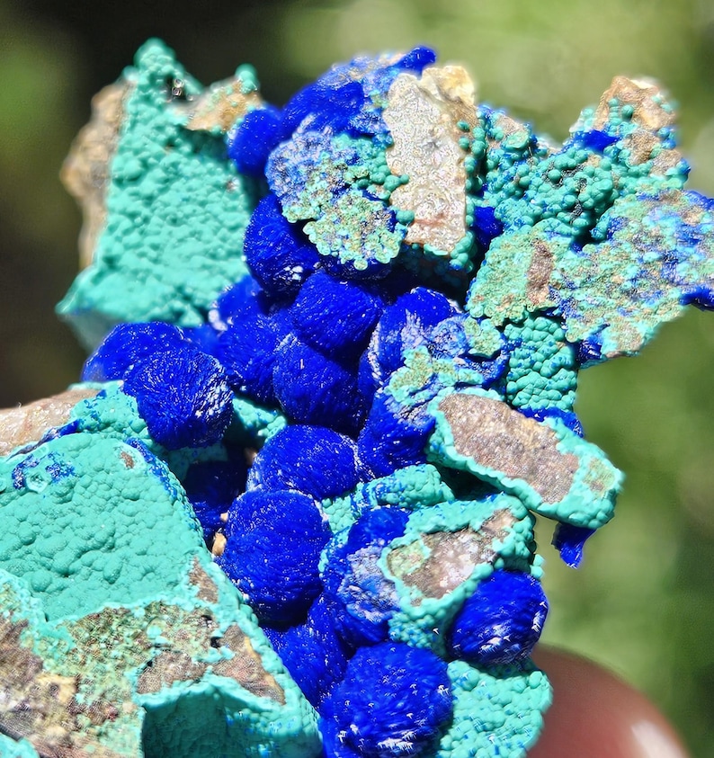Op de afbeelding: Close-up van een mineraalmonster met azuriet en malachiet. De afbeelding toont diepblauwe azurietclusters naast getextureerde, turkooisgroene malachiet. De mineraalformatie heeft een ruwe, natuurlijke uitstraling met bruine matrix.